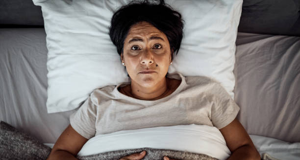 Anxious woman lying awake in bed at night, staring at the ceiling