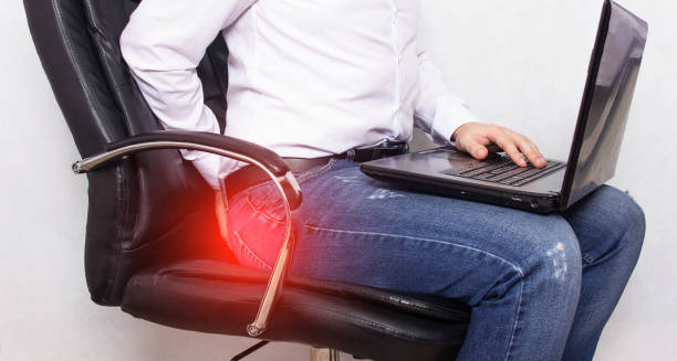 Man experiencing discomfort from prolonged sitting, highlighting haemorrhoid risk