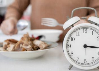 Clock beside food plate symbolising meal timing for heartburn prevention