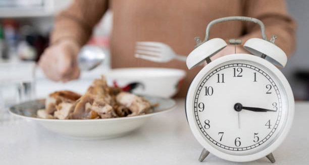 Clock beside food plate symbolising meal timing for heartburn prevention