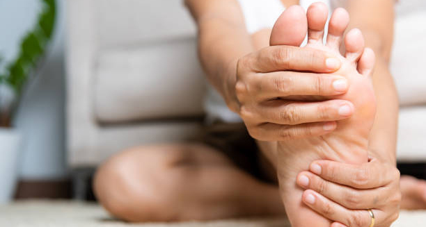 Person holding foot while sitting, possibly experiencing foot drop symptoms