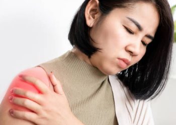 Woman holding shoulder in pain indicating symptoms of frozen shoulder
