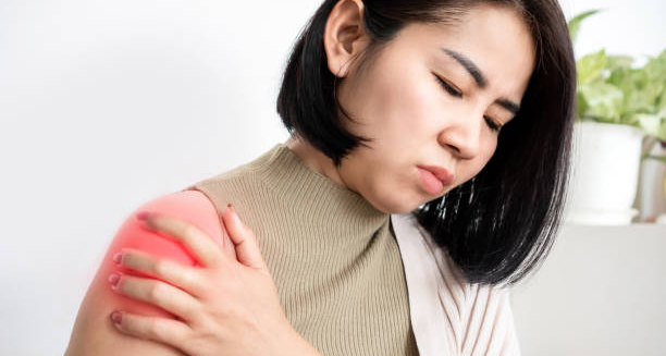 Woman holding shoulder in pain indicating symptoms of frozen shoulder
