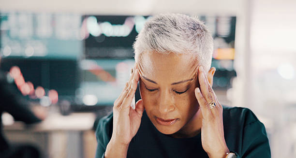 Woman with grey hair touching her temples in pain, showing symptoms of Giant Cell Arteritis