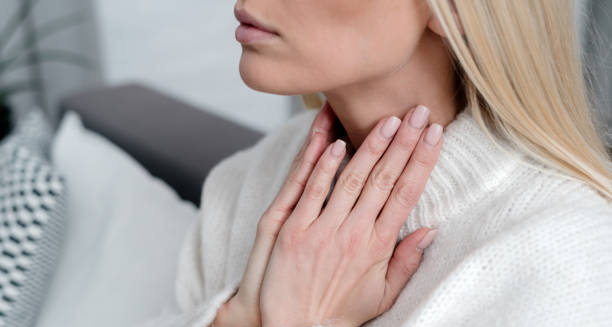 Woman holding sore throat due to glandular fever symptoms