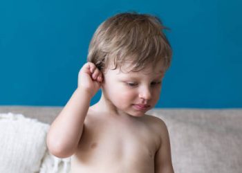 Toddler touching ear with discomfort, showing signs of glue ear