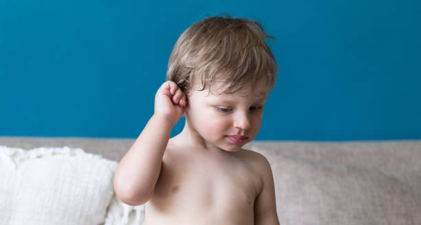 Toddler touching ear with discomfort, showing signs of glue ear