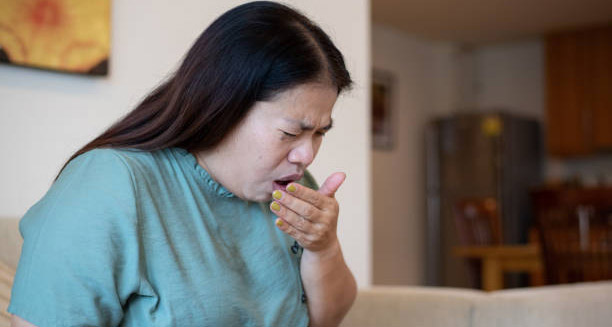 Woman coughing on a sofa, showing signs of illness possibly linked to HIV