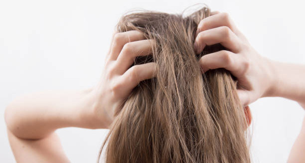 Person scratching scalp intensely, showing common symptoms of head lice or nits