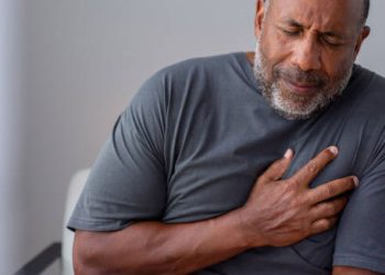 Elderly man clutching chest in pain showing symptoms of a heart attack
