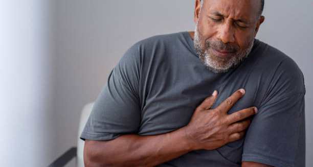 Elderly man clutching chest in pain showing symptoms of a heart attack
