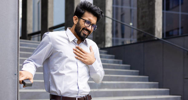 Man clutching his chest in pain while standing near stairs, showing signs of heart failure