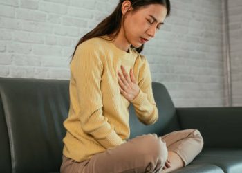 Woman clutching chest in discomfort due to heartburn symptoms