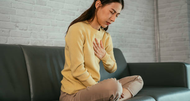 Woman clutching chest in discomfort due to heartburn symptoms