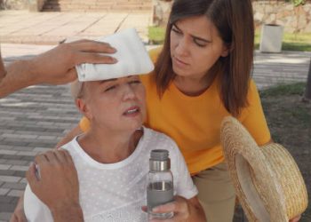 Elderly woman with heat exhaustion receiving help outdoors