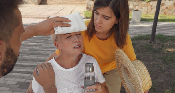 Elderly woman with heat exhaustion receiving help outdoors