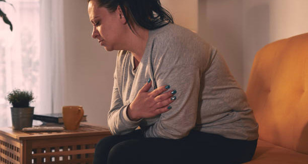 Woman in visible discomfort clutching her abdomen and chest during a heavy period