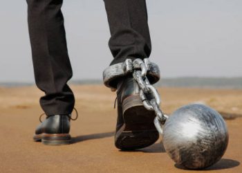 Man walking with heavy ball and chain symbolising mobility limitations in hereditary spastic paraplegia
