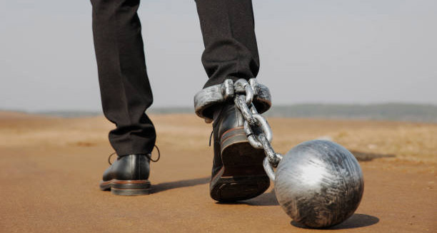 Man walking with heavy ball and chain symbolising mobility limitations in hereditary spastic paraplegia