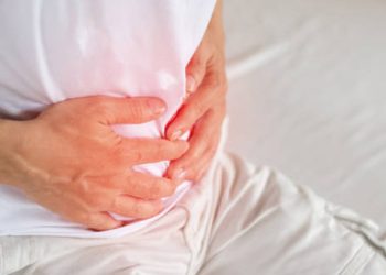 Man clutching his lower abdomen in pain, indicating symptoms of a hernia