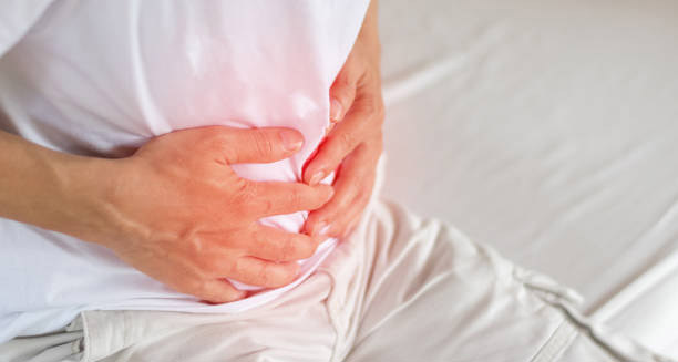 Man clutching his lower abdomen in pain, indicating symptoms of a hernia