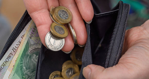 Close-up of hands holding coins and a wallet filled with money, symbolising difficulty discarding possessions