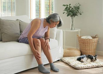 Older woman experiencing leg discomfort, a possible symptom of hookworm infection