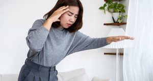 Woman feeling dizzy and holding her head due to low blood pressure