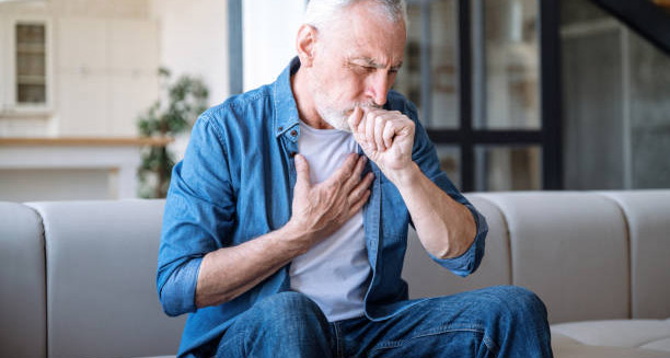 Elderly man coughing and holding chest, showing signs of idiopathic pulmonary fibrosis