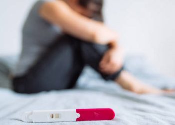 Negative pregnancy test with distressed woman in background