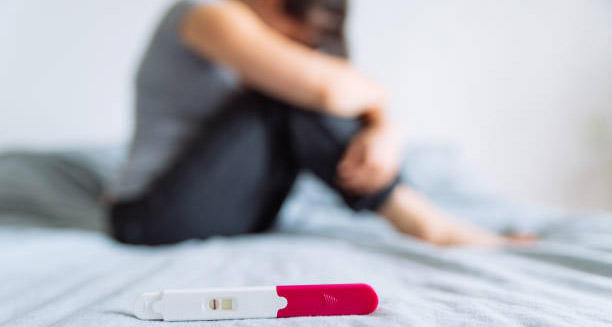 Negative pregnancy test with distressed woman in background