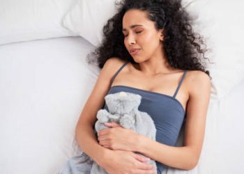 Woman lying in bed holding her stomach in pain due to inflammatory bowel disease