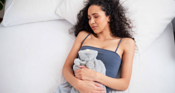 Woman lying in bed holding her stomach in pain due to inflammatory bowel disease