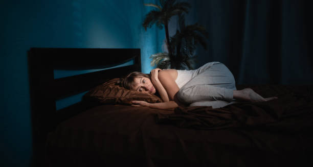 Woman curled up in bed looking distressed during the night