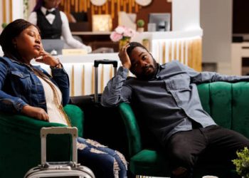 Tired couple sitting in a hotel lobby showing signs of jet lag after travel