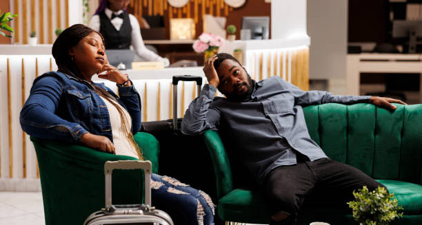 Tired couple sitting in a hotel lobby showing signs of jet lag after travel