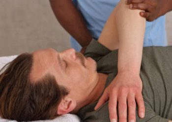 Physiotherapist treating a patient's shoulder to relieve frozen shoulder