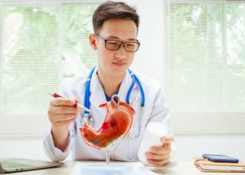 Doctor explaining gastritis treatment using stomach model