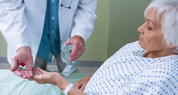 Doctor giving medication and water to elderly patient in hospital bed