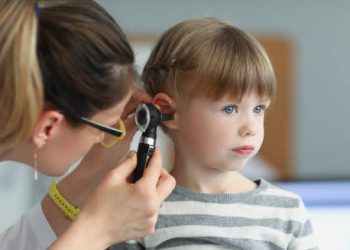 Doctor using otoscope to examine a child's ear for glue ear treatment options