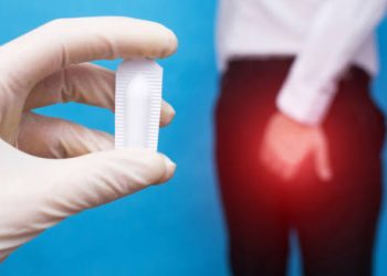 Doctor holding suppository for haemorrhoid treatment