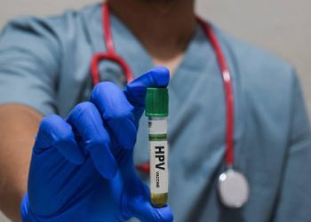 Doctor holding an HPV-labelled test tube, illustrating medical testing and diagnosis procedures