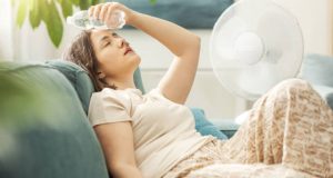 Woman cooling down with water and a fan to treat heat exhaustion