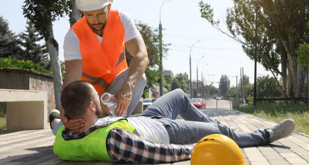 Construction worker helping colleague with heatstroke by giving water