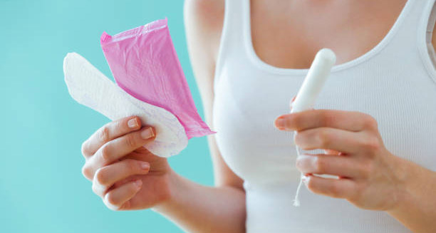 Woman holding a sanitary pad and tampon as part of heavy period treatment options