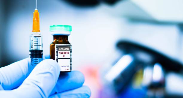 Medical syringe and vial labelled Hepatitis C vaccine held by gloved hand