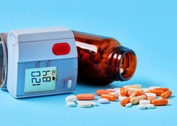 Blood pressure monitor and medication for treating hypertension on blue background