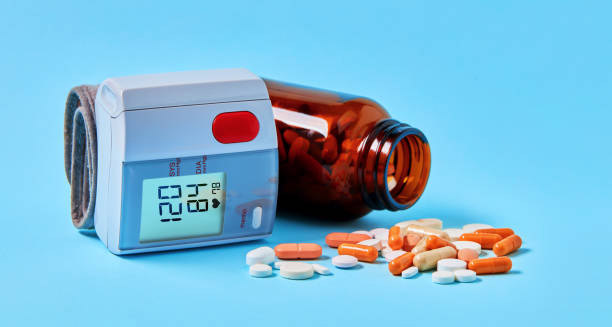 Blood pressure monitor and medication for treating hypertension on blue background