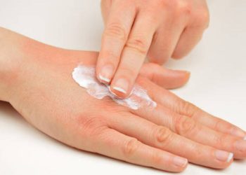Applying moisturising cream to hand as treatment for ichthyosis