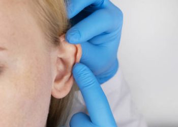 Medical professional examining an infected ear piercing